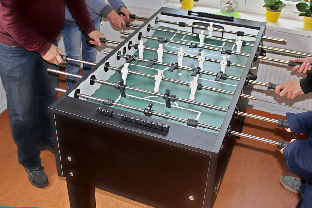 Vier Personen spielen im Freizeitraum Tischkicker.