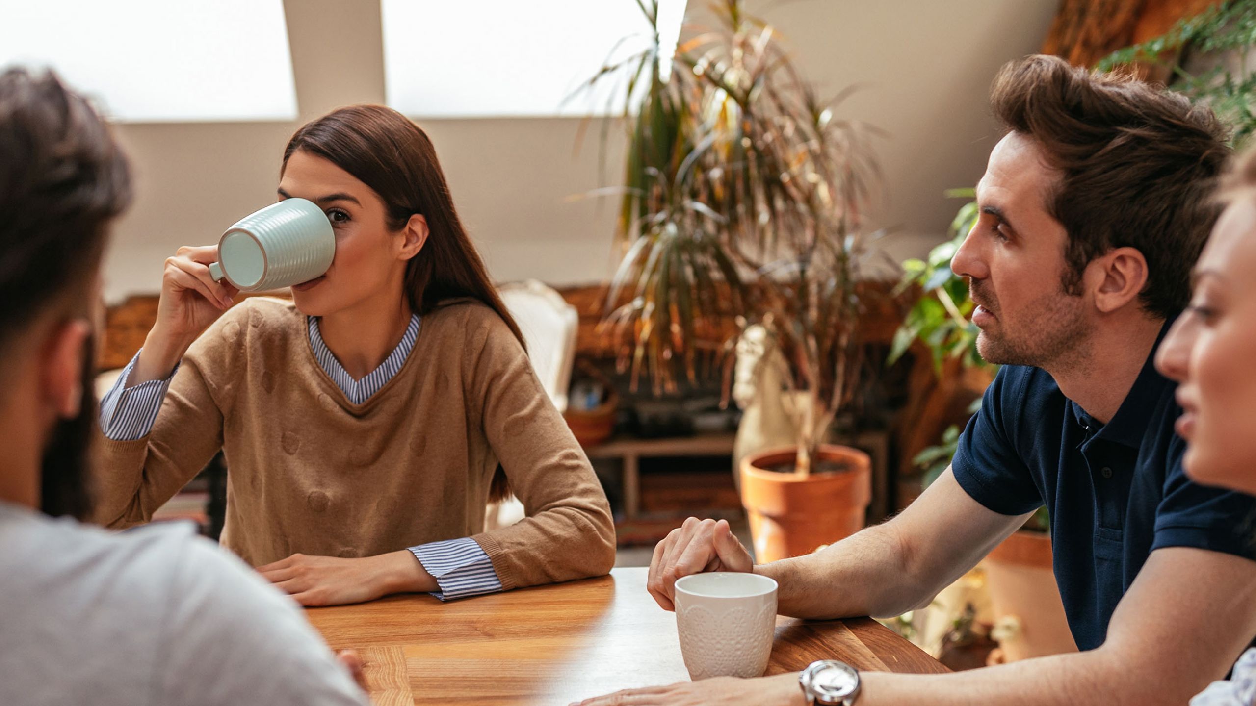Eine Gruppe von Menschen sitzt am Tisch und trinkt Kaffee.