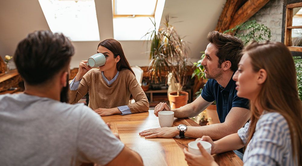 Eine Gruppe von Menschen sitzt am Tisch und trinkt Kaffee.