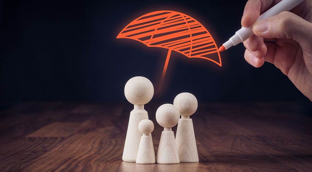 Ein gemalter Regenschirm schützt eine Familie aus Holzpuppen.